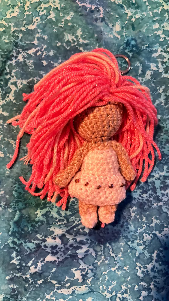 crocheted feminine doll with pink hair, white dress with bead detail, keychain attachment